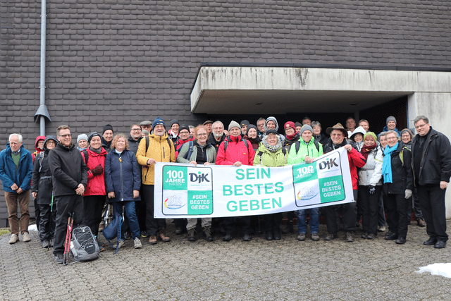 Gruppenfoto von etwa 50 Menschen vor einem Geb&auml;ude, die ein Banner mit der Aufschrift &bdquo;SEIN BESTES GEBEN&ldquo; halten.