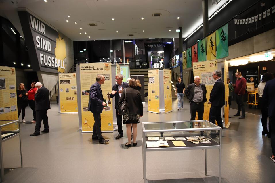 Ausstellung im Fu&szlig;ballmuseum mit Besuchern, Informationsst&auml;nden und einem Glasvitrinen in der Mitte des Raumes.