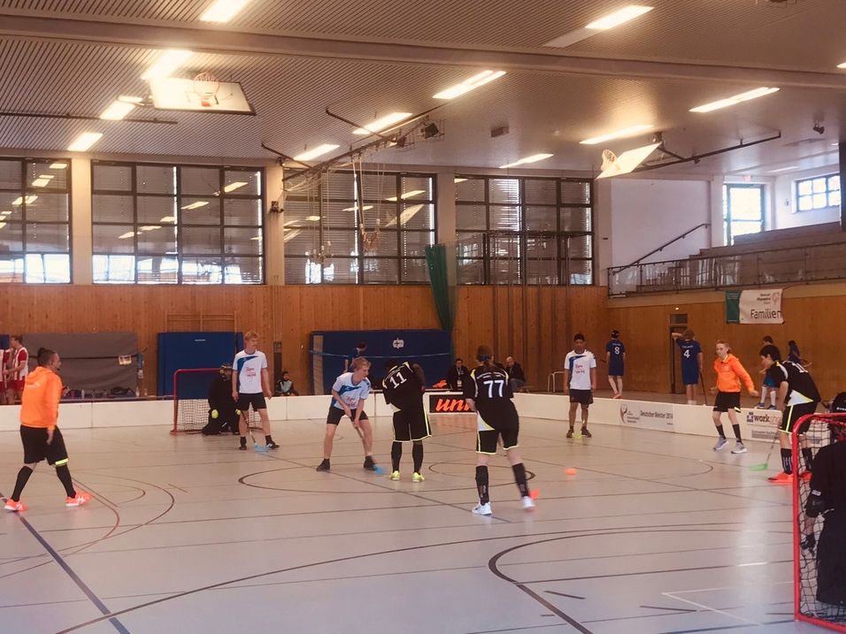In einer Sporthalle spielen zwei Teams Futsal, der Ball wird in der Mitte des Spielfelds gef&uuml;hrt.