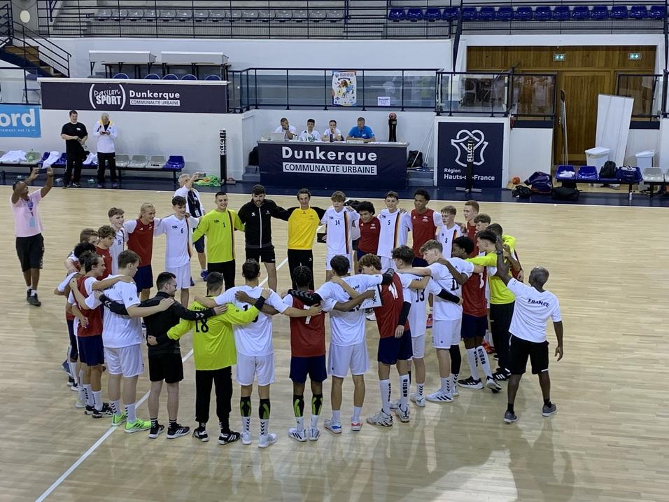 Zwei Teams stehen sich umarmend in einem Sporthalle gegen&uuml;ber. Spieler in roten und wei&szlig;en Trikots bilden einen Kreis.