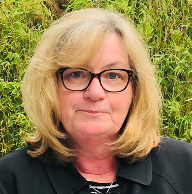 Frau mit blonden, schulterlangen Haaren und Brille, vor gr&uuml;nem Hintergrund.