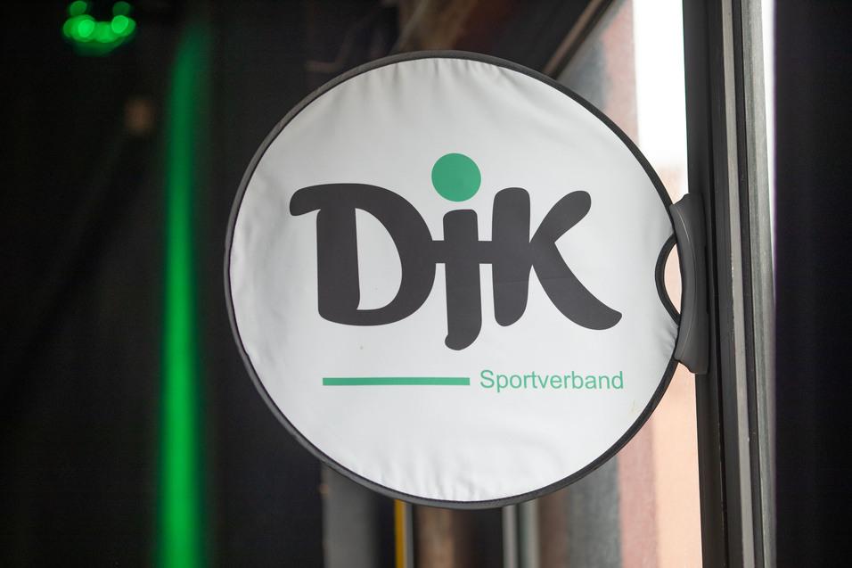 Runder Au&szlig;enschild des DJK Sportverbands mit gr&uuml;ner Schrift auf wei&szlig;em Hintergrund.