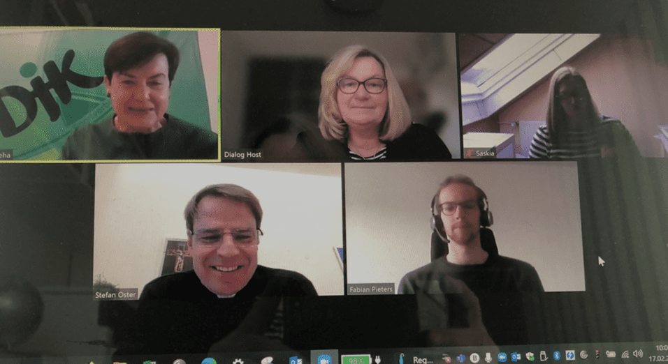 Videokonferenz mit f&uuml;nf Personen, darunter eine Frau mit gr&uuml;nem Oberteil und vier weitere Teilnehmer in unterschiedlichen Outfits.