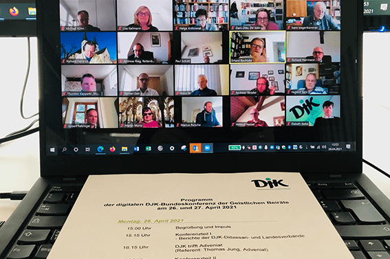 Screenshot einer Videokonferenz mit mehreren Teilnehmern auf einem Laptop, darunter das Programmheft der Veranstaltung.
