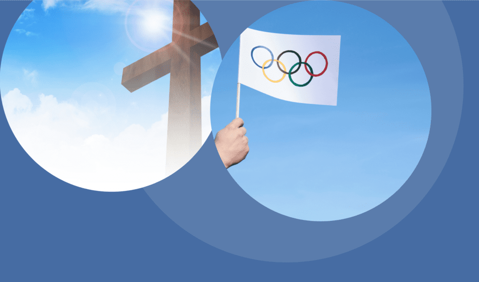 Hand h&auml;lt eine Fahne mit den Olympischen Ringen vor einem blauen Himmel und einem Holz-Kreuz im Hintergrund.