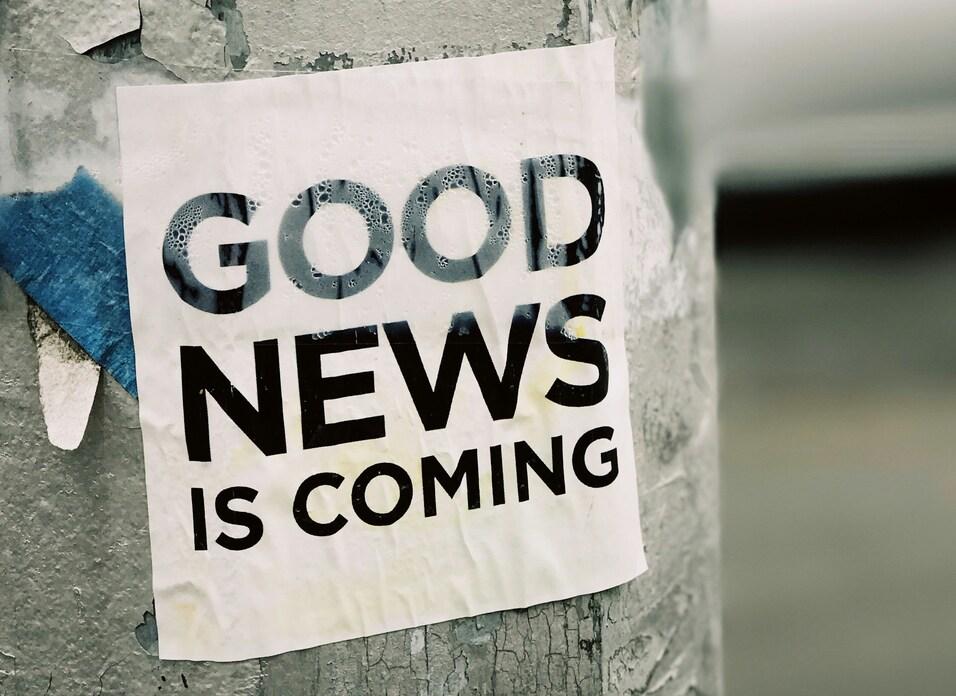 Plakat mit der Aufschrift &bdquo;GOOD NEWS IS COMING&ldquo; auf einem grauen Laternenpfahl.